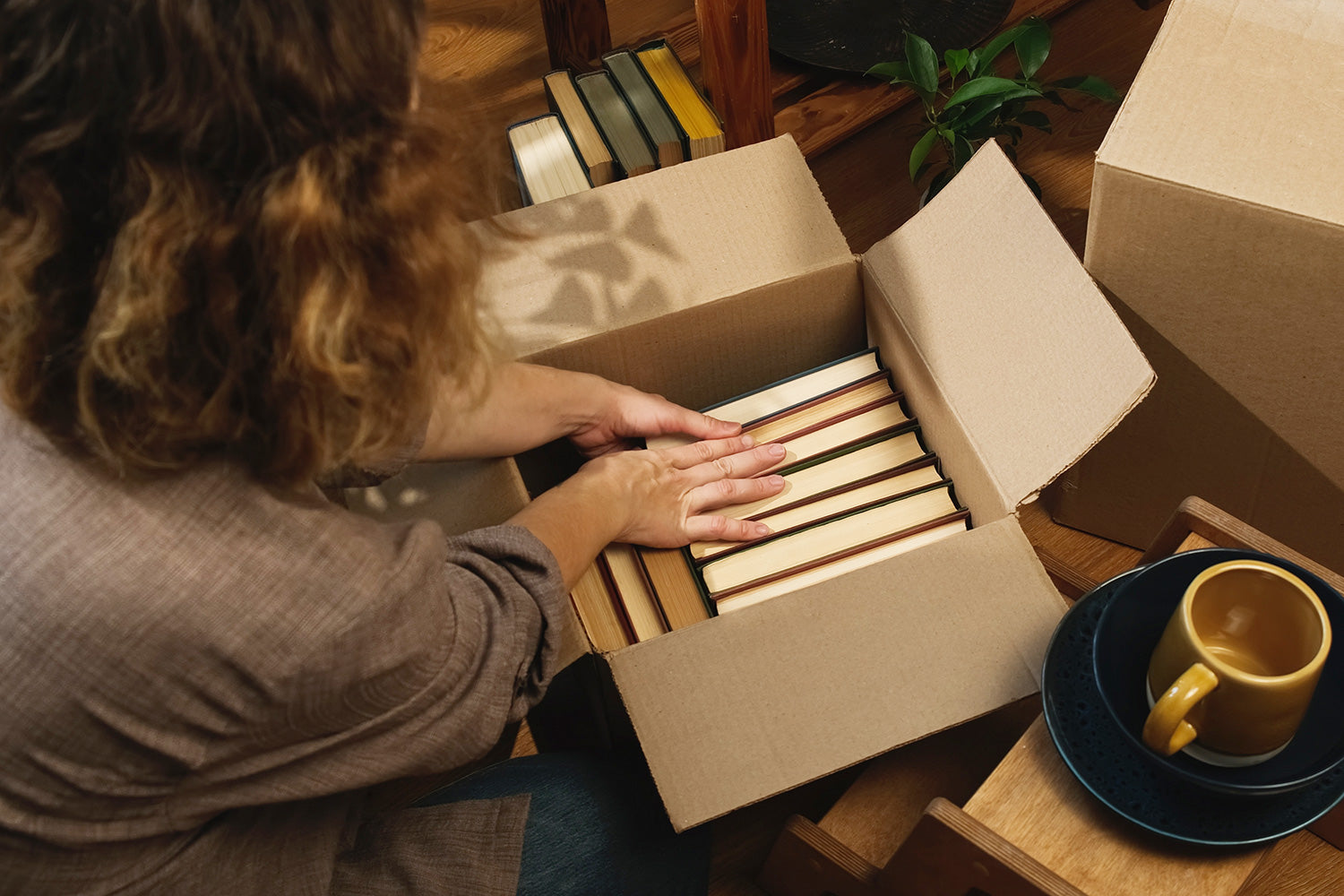 Move Management services unpacking a box of books on a wooden floor.
